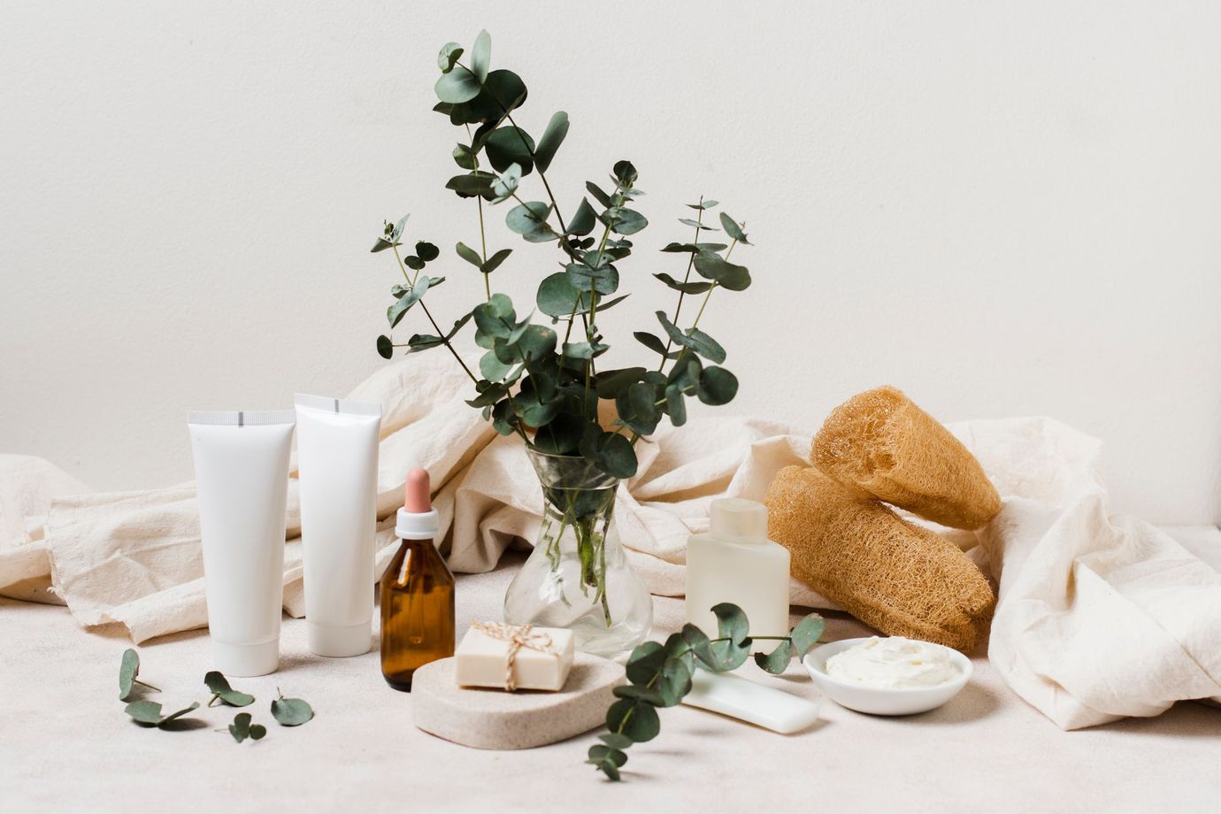 Produits de spa et eucalyptus sur une table claire avec des serviettes et des bols en bois.