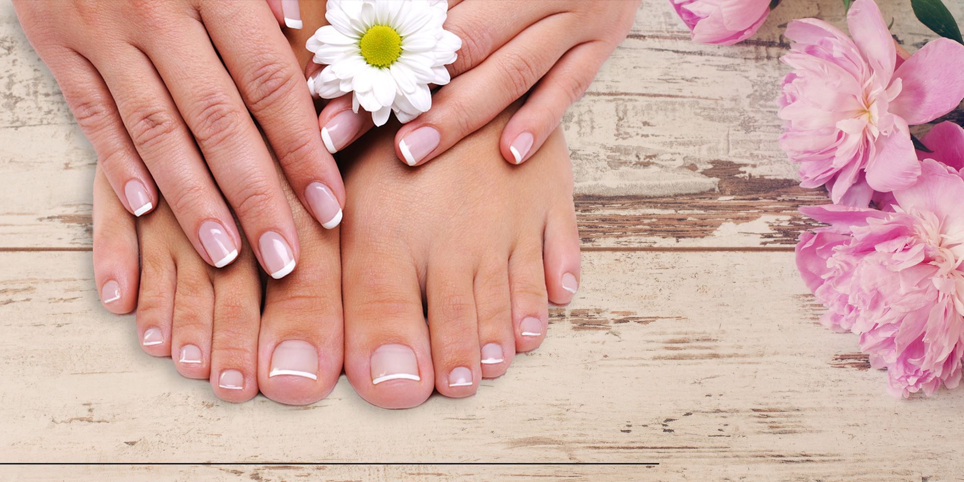 Mains et pieds avec manucure française, fleur blanche et fleurs roses sur un fond en bois rustique