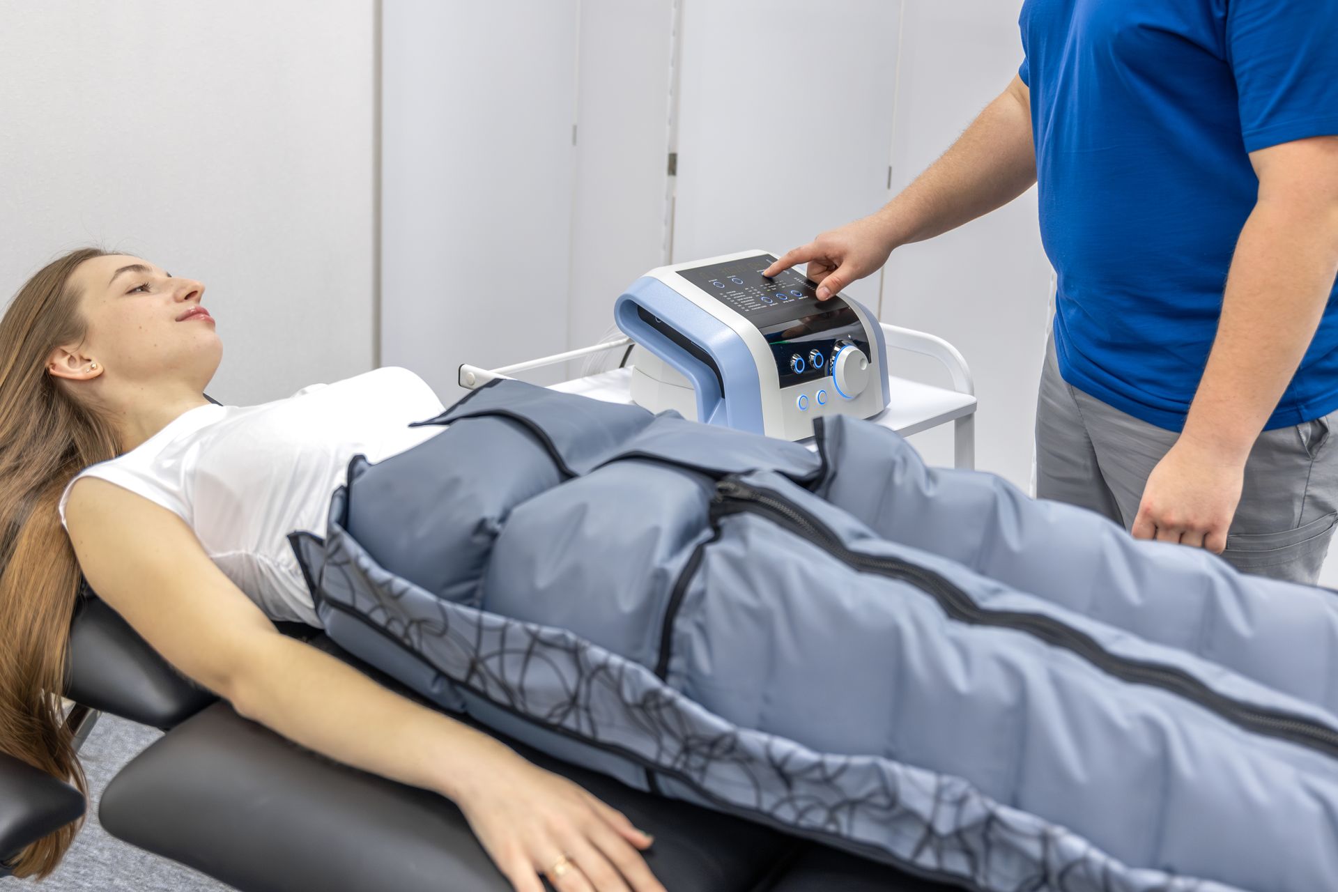 Une femme allongée dans une botte de compression thérapeutique pendant qu'un clinicien ajuste l'unité de contrôle