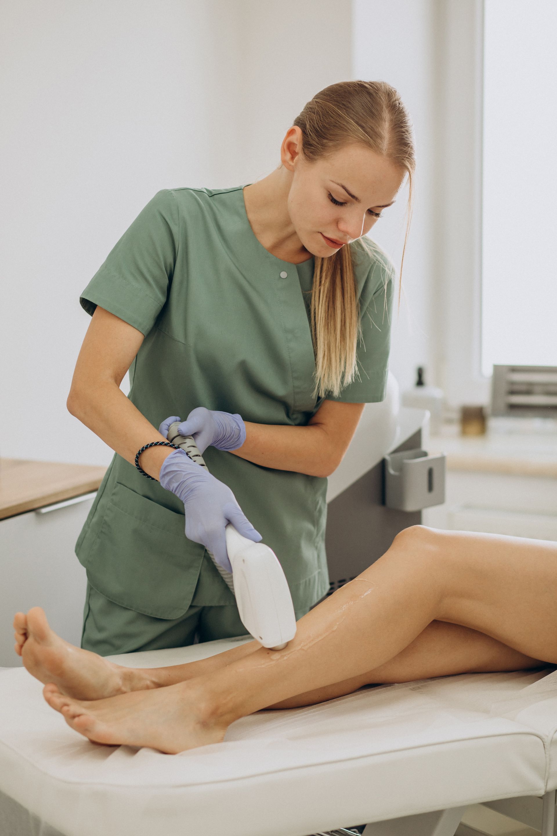 Une technicienne de spa utilise un appareil portatif sur la jambe d'un client pendant un soin.
