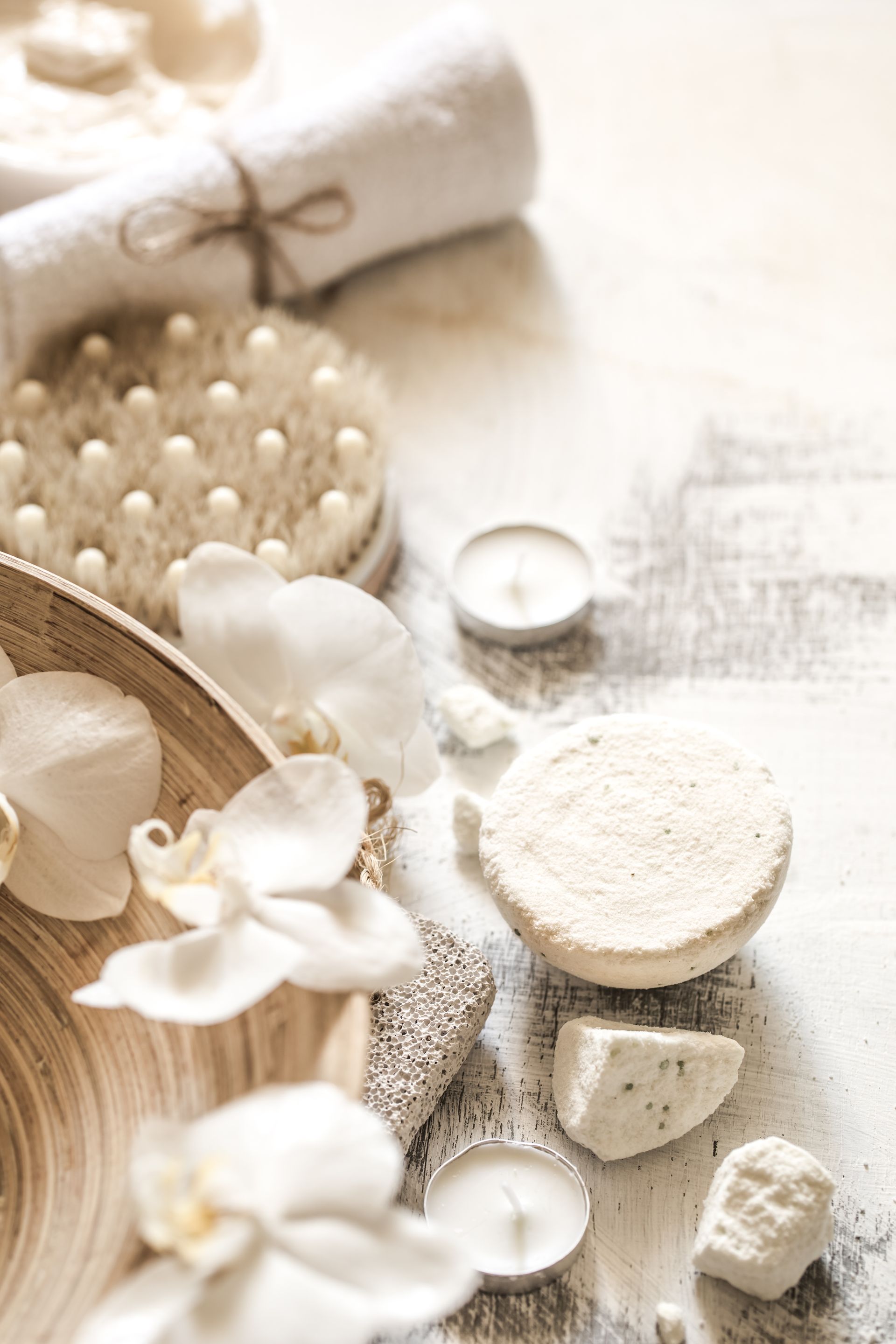 Nature morte de spa avec accessoires de bain beiges, fleurs blanches et luffas naturels sur une surface en lin doux