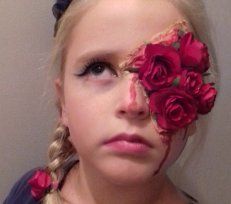 Jeune personne avec une tresse blonde et des roses roses couvrant un œil, regardant vers le haut avec une expression sérieuse.