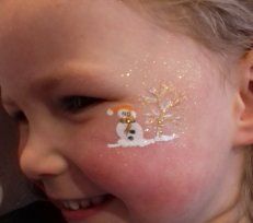 Gros plan sur un enfant souriant avec un petit bonhomme de neige peint sur la joue.