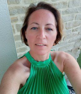 Selfie en gros plan d'une personne en haut dos nu vert contre un mur de pierre.