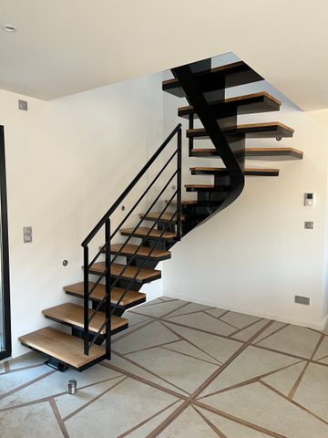Un escalier flottant moderne avec des marches en bois, une structure et une rampe en métal noir, situé dans une pièce au sol carrelé.