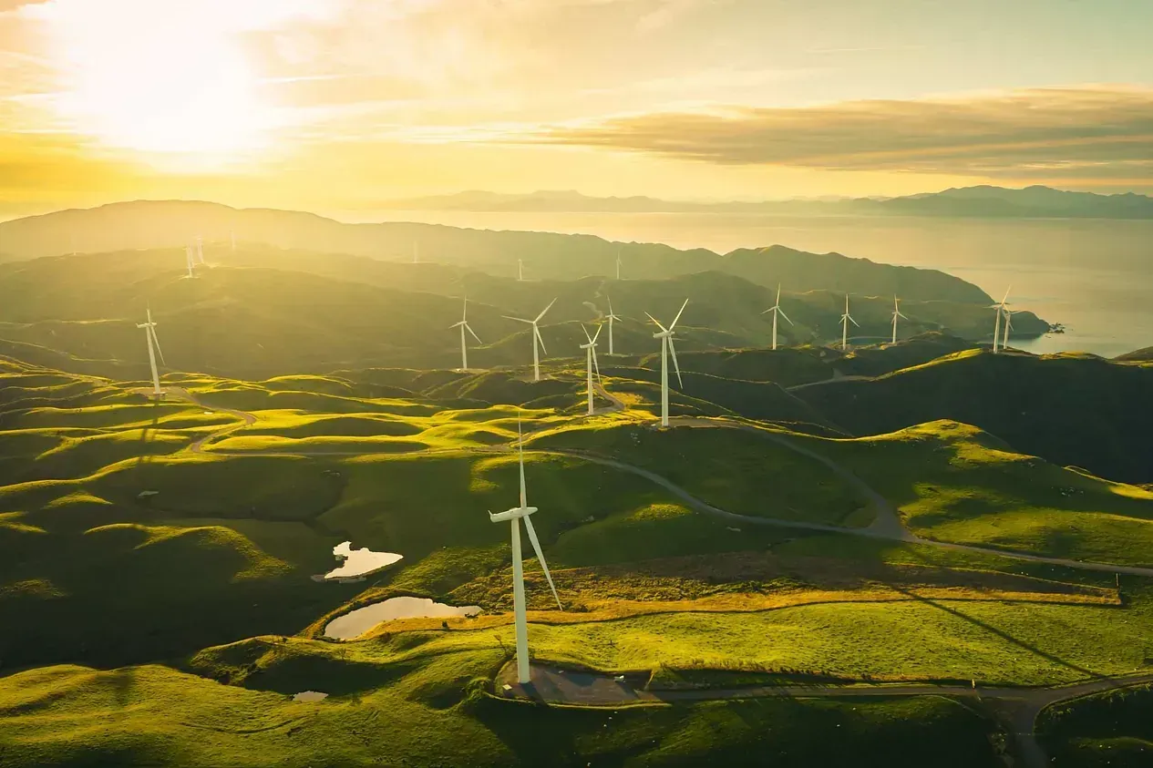 Una vista aérea de un parque eólico en una colina al atardecer.