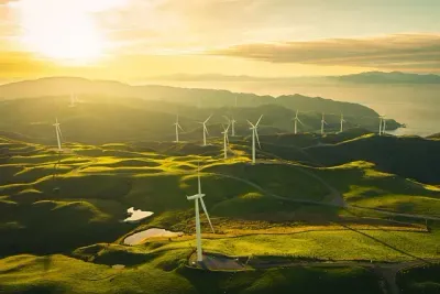 Una vista aérea de un parque eólico en una colina al atardecer.