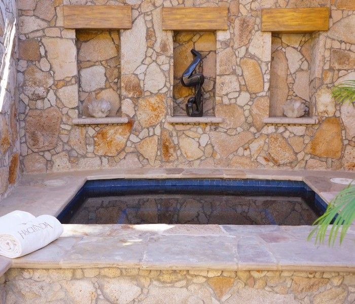 Couple in a pool, smiling with arms around each other. Tropical setting, blue sky.