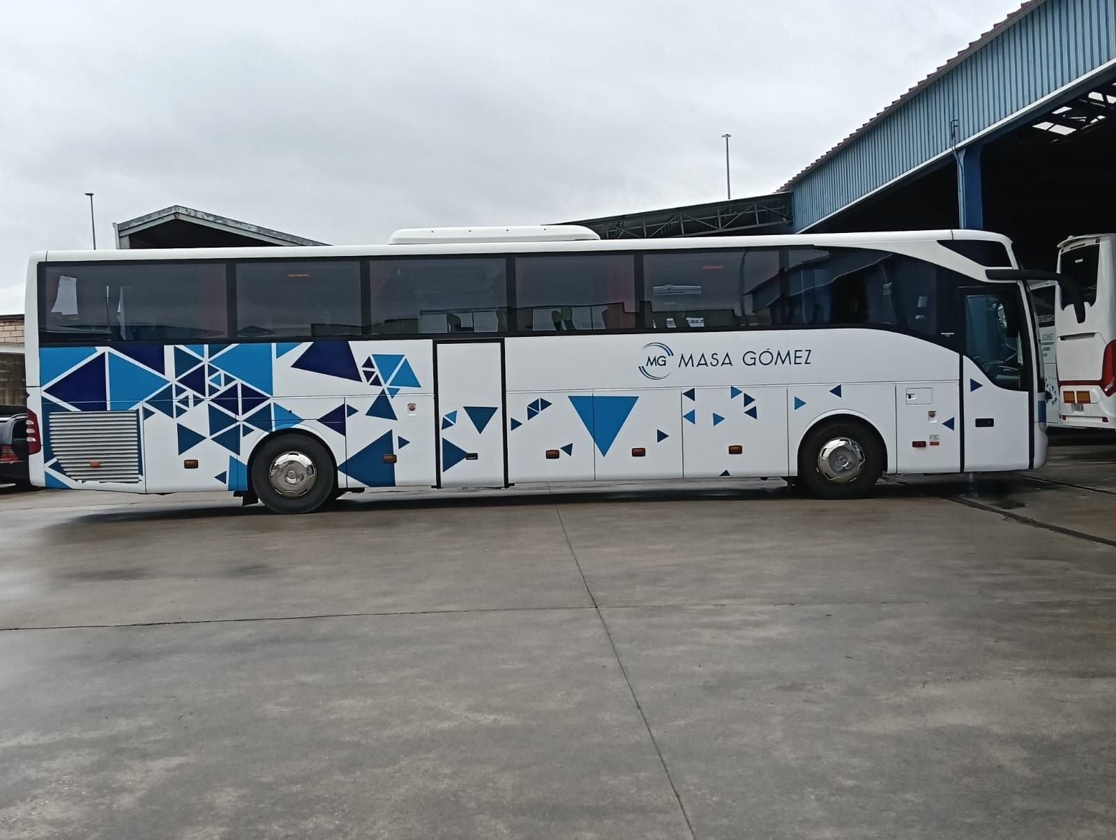 Un autobús blanco y azul está estacionado en un estacionamiento.