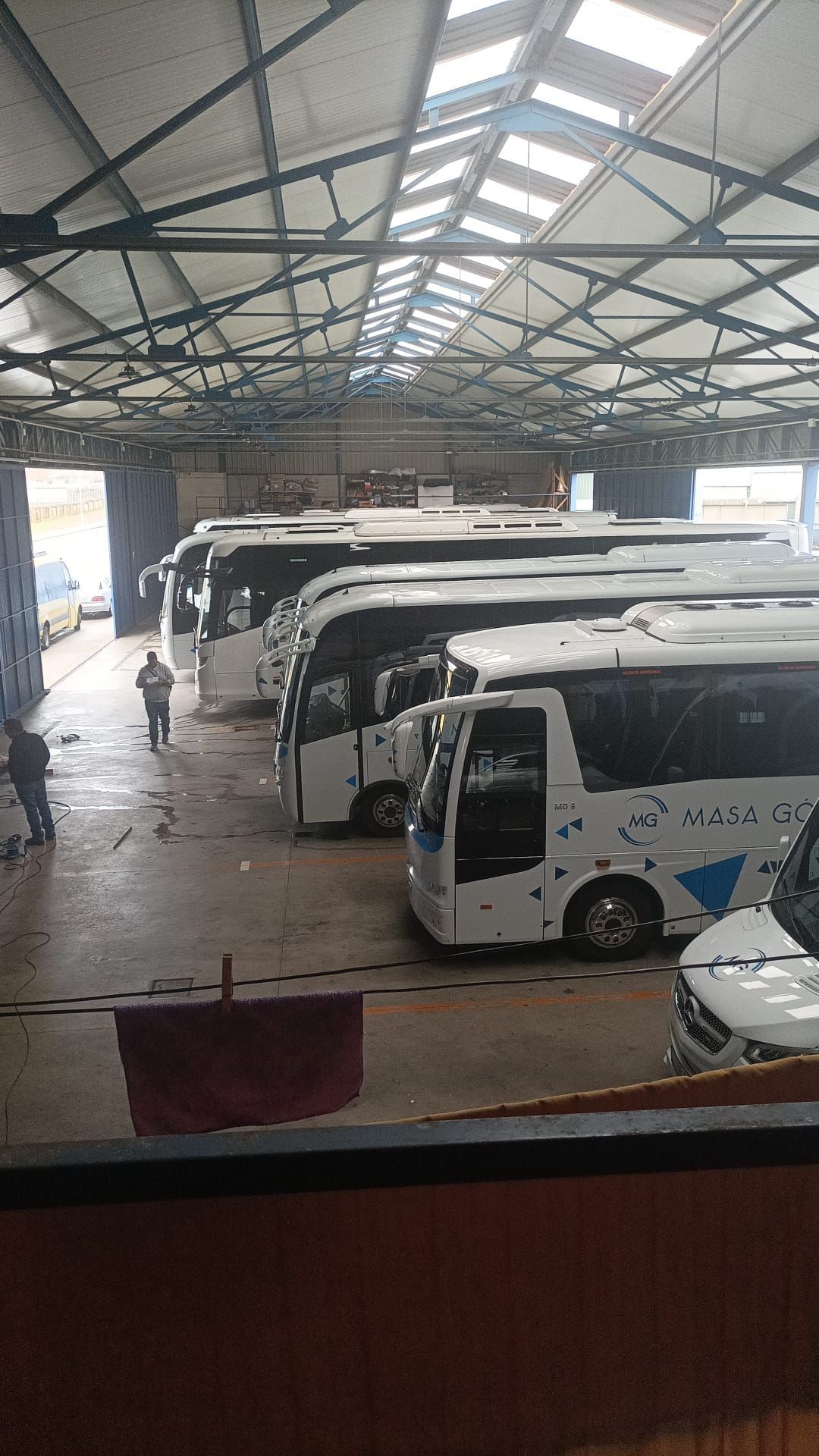 Una fila de autobuses están estacionados en un almacén.