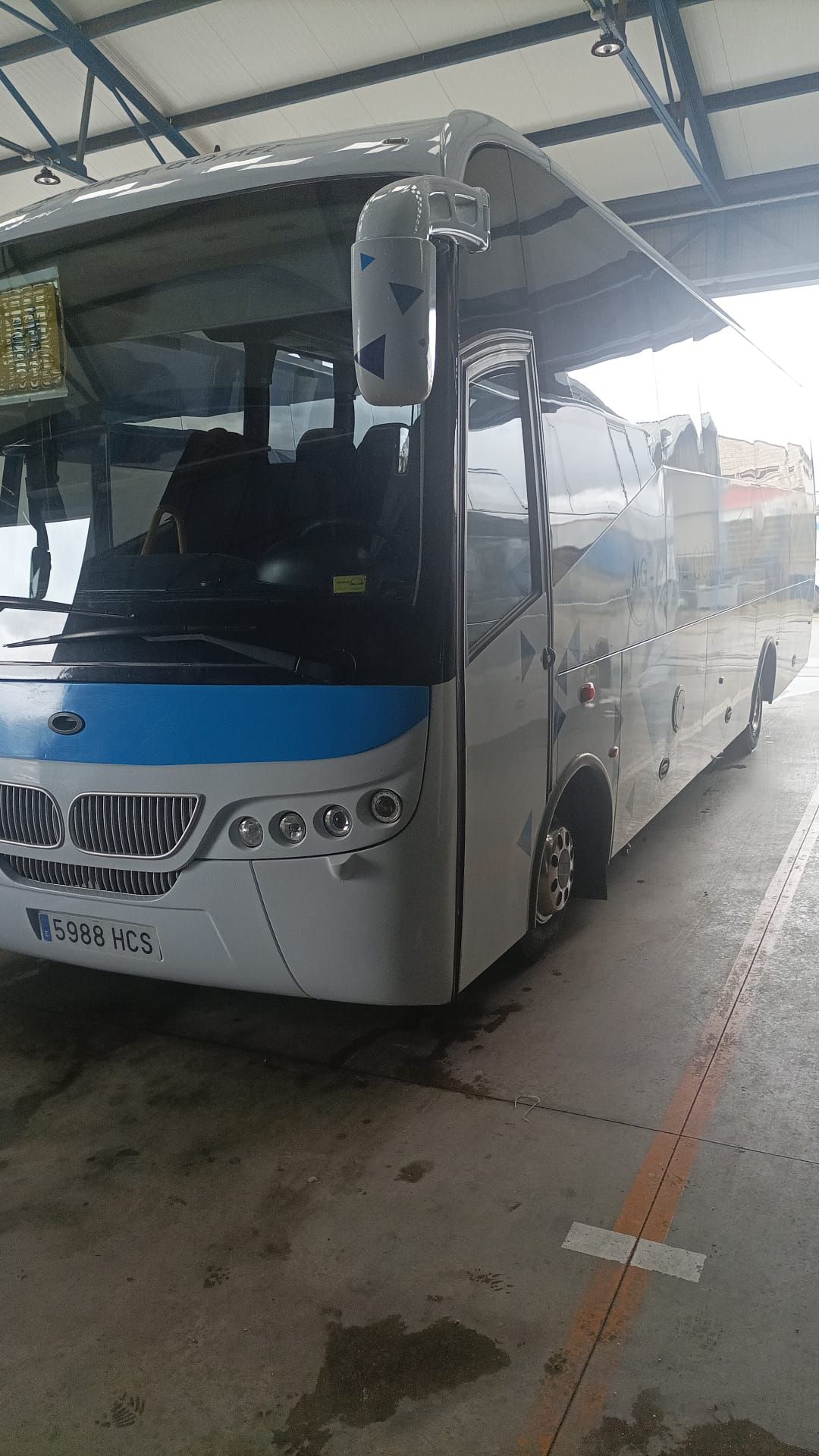 Un autobús blanco y azul está estacionado en un estacionamiento.