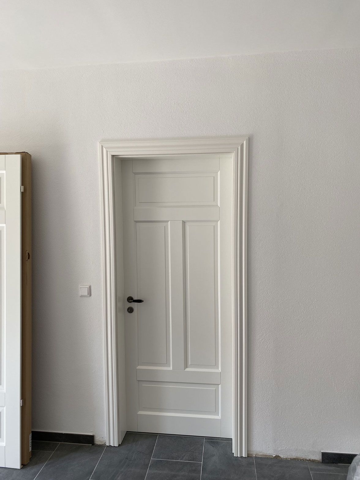 In der Mitte eines Raumes ist eine weiße Tür.