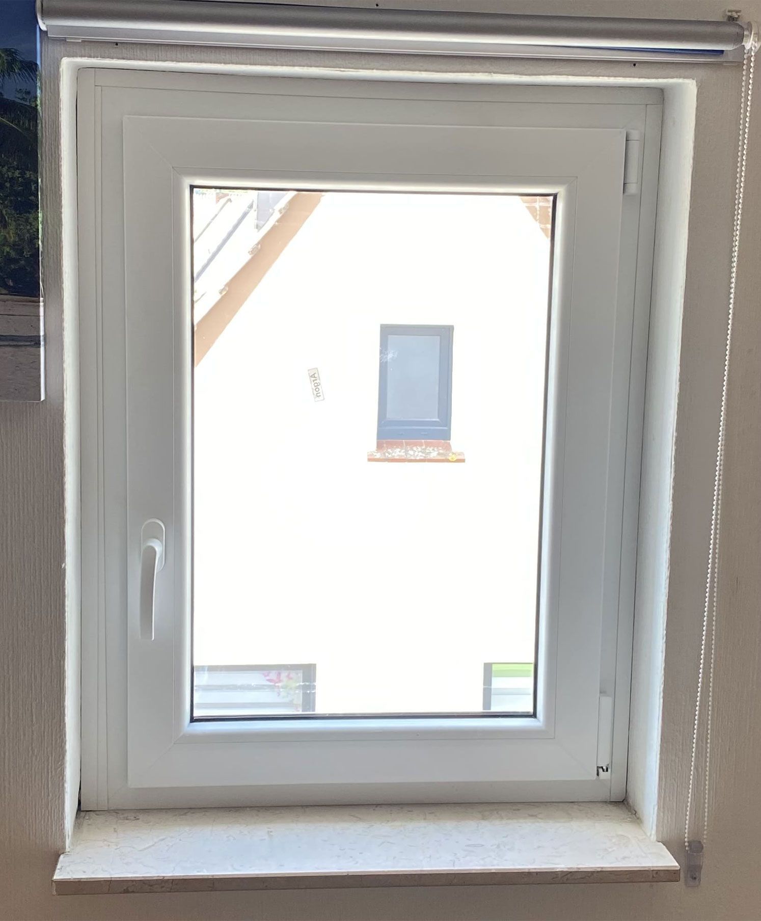 Ein weißes Fenster mit Blick auf ein Haus im Hintergrund.