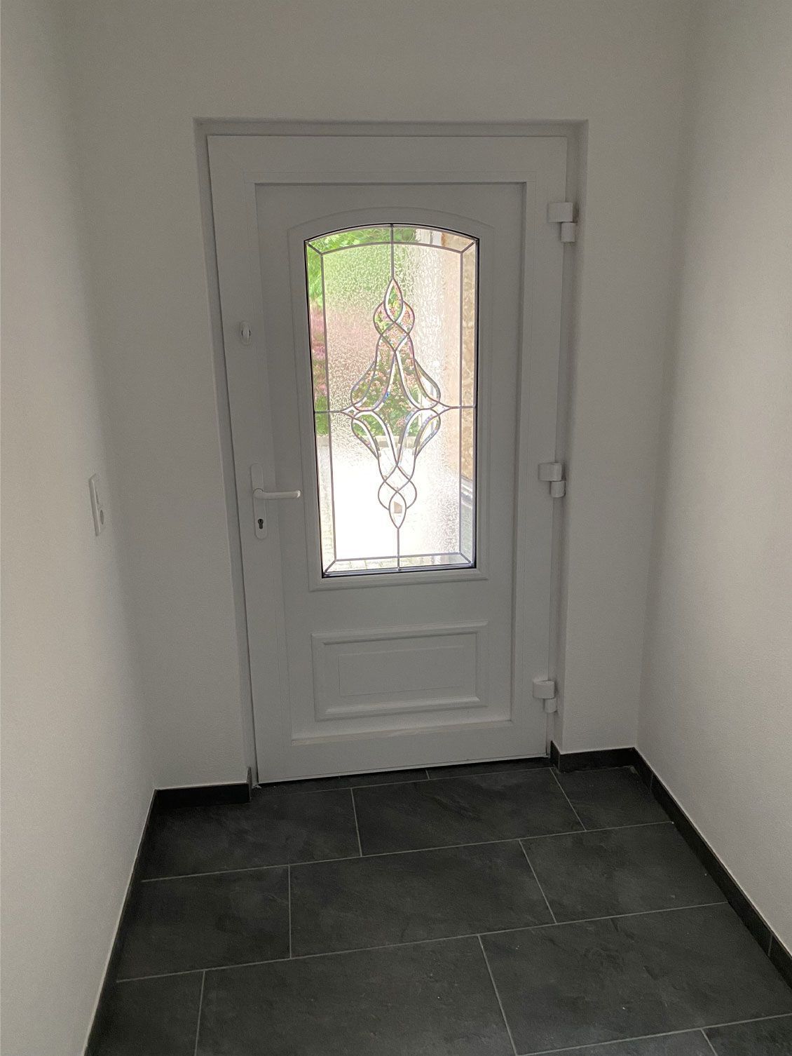 Eine weiße Tür mit einem Buntglasfenster in einem Flur.