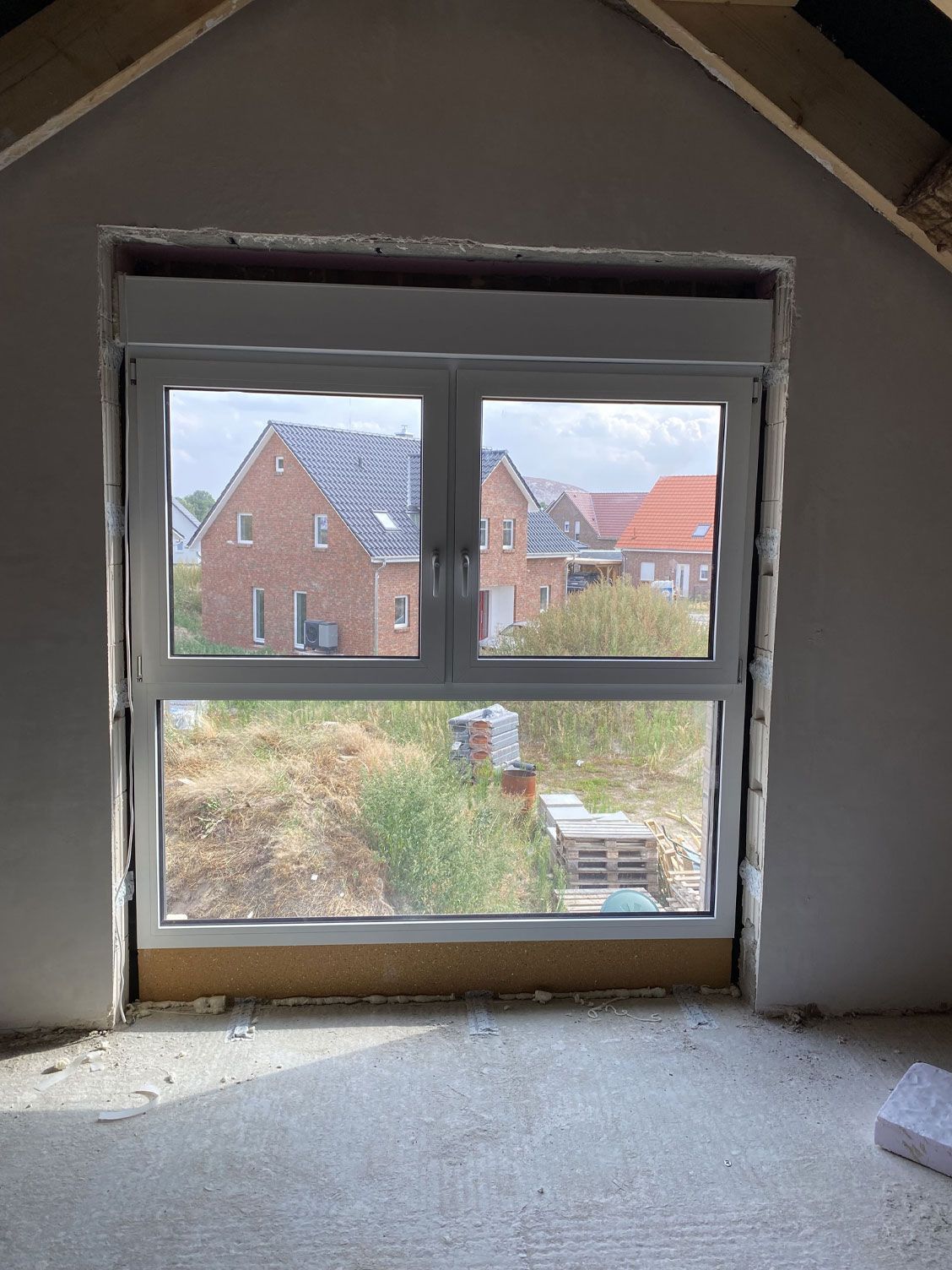 Ein Fenster in einem Zimmer mit Aussicht auf ein Backsteinhaus.