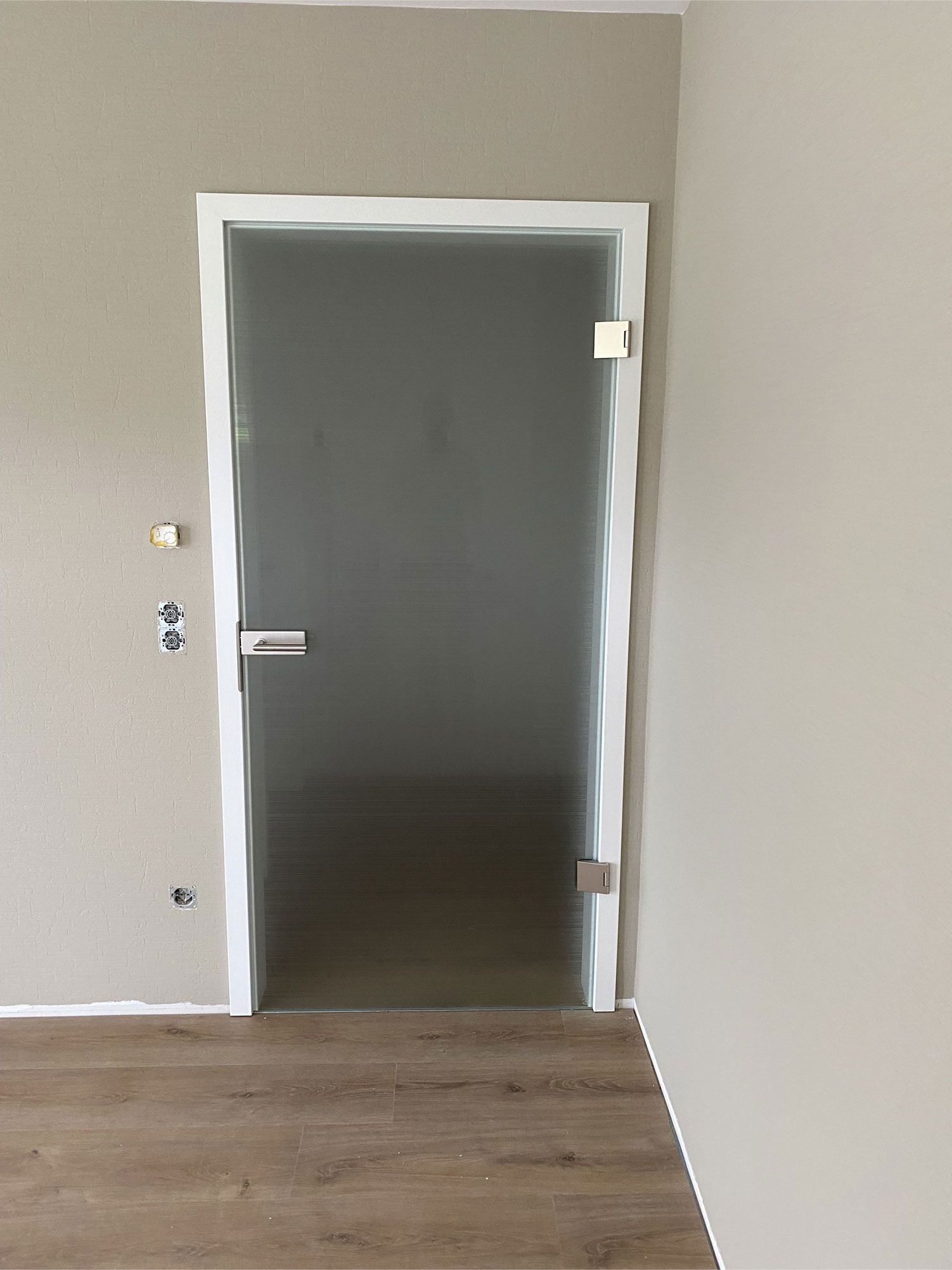 In einem Raum mit Holzboden steht eine Glastür offen.