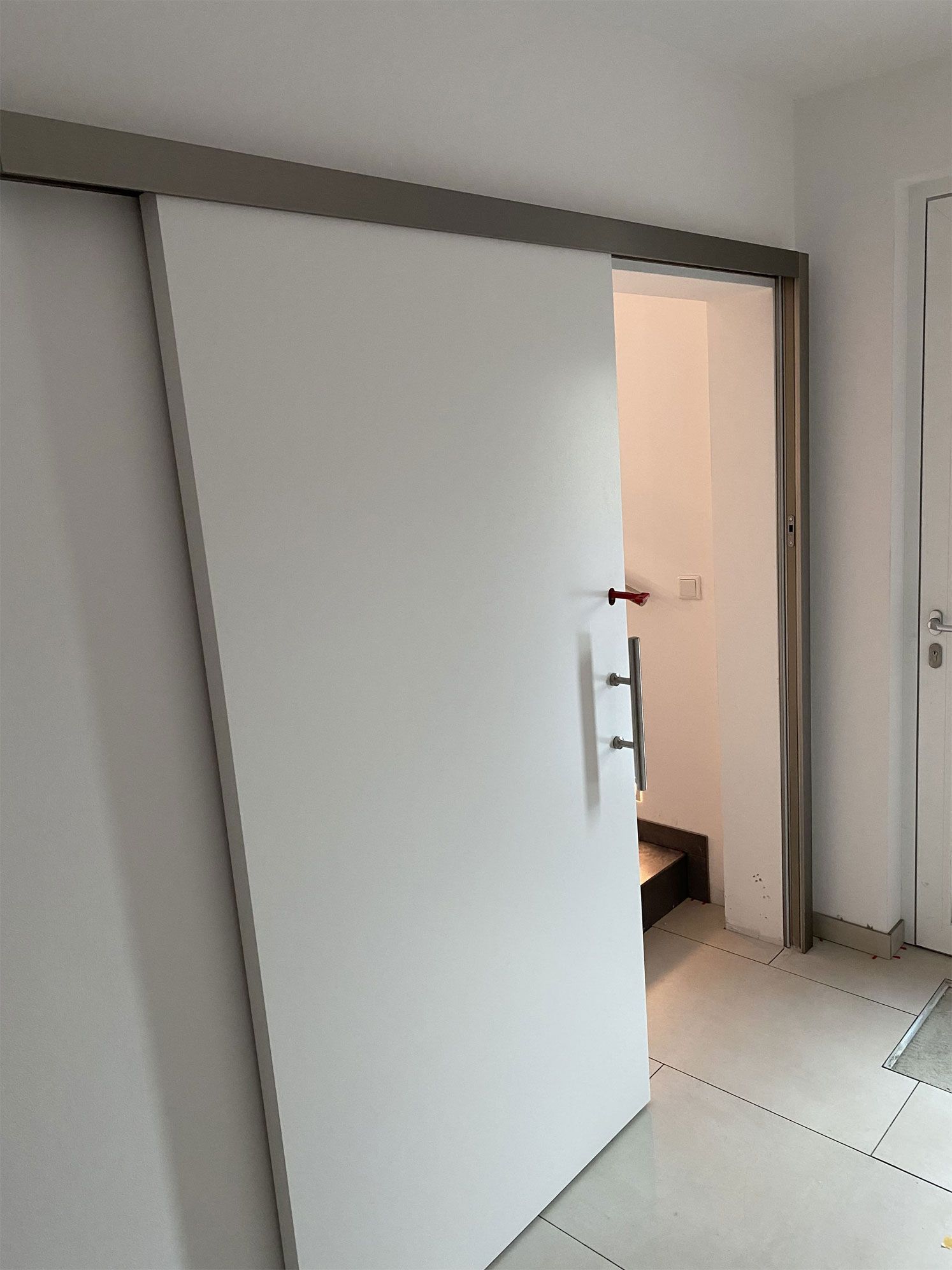 Eine weiße Schiebetür führt zu einem Badezimmer