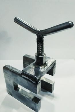 Una herramienta de metal con mango reposa sobre una superficie blanca.