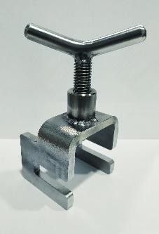 Un objeto de metal con mango está sobre una superficie blanca.