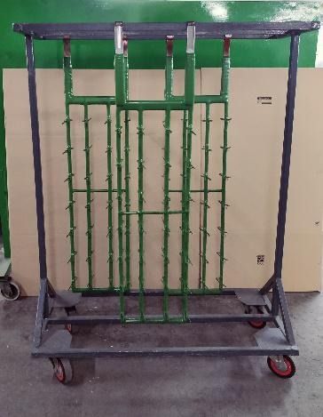 Un estante de metal verde con ruedas se encuentra frente a una pared verde.