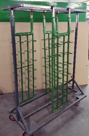 Un estante de metal verde con ruedas está colocado sobre un piso de concreto.