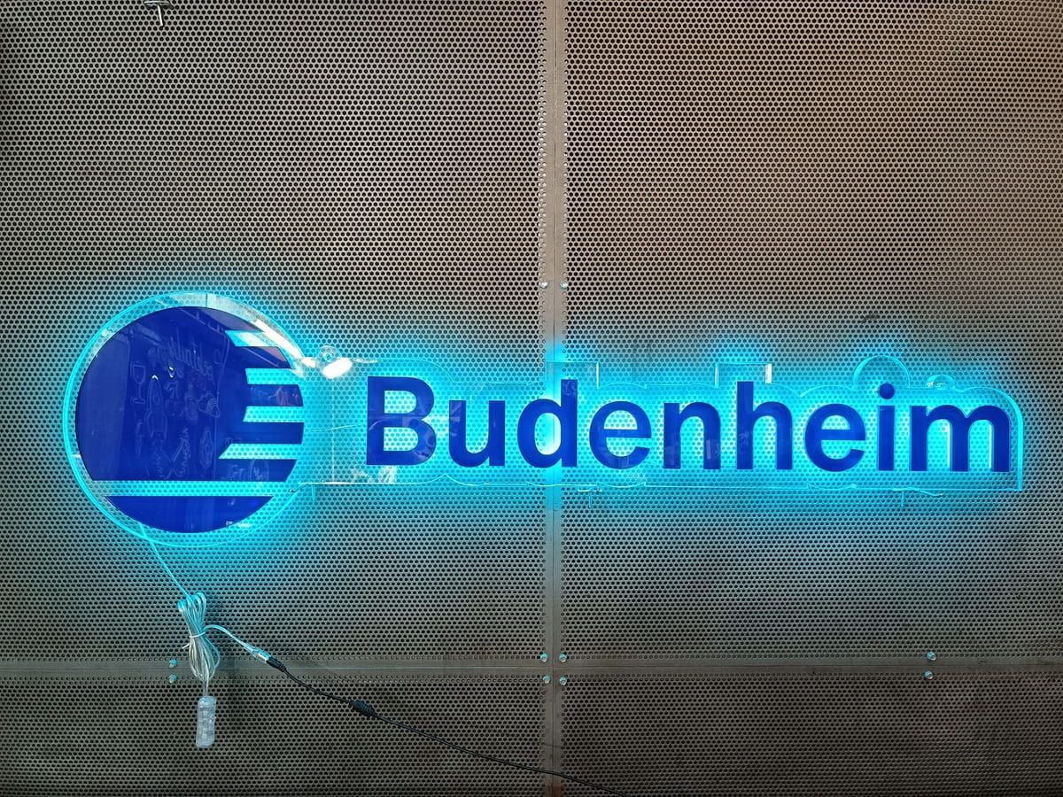 Un letrero de neón azul que dice Budenheim en una pared.