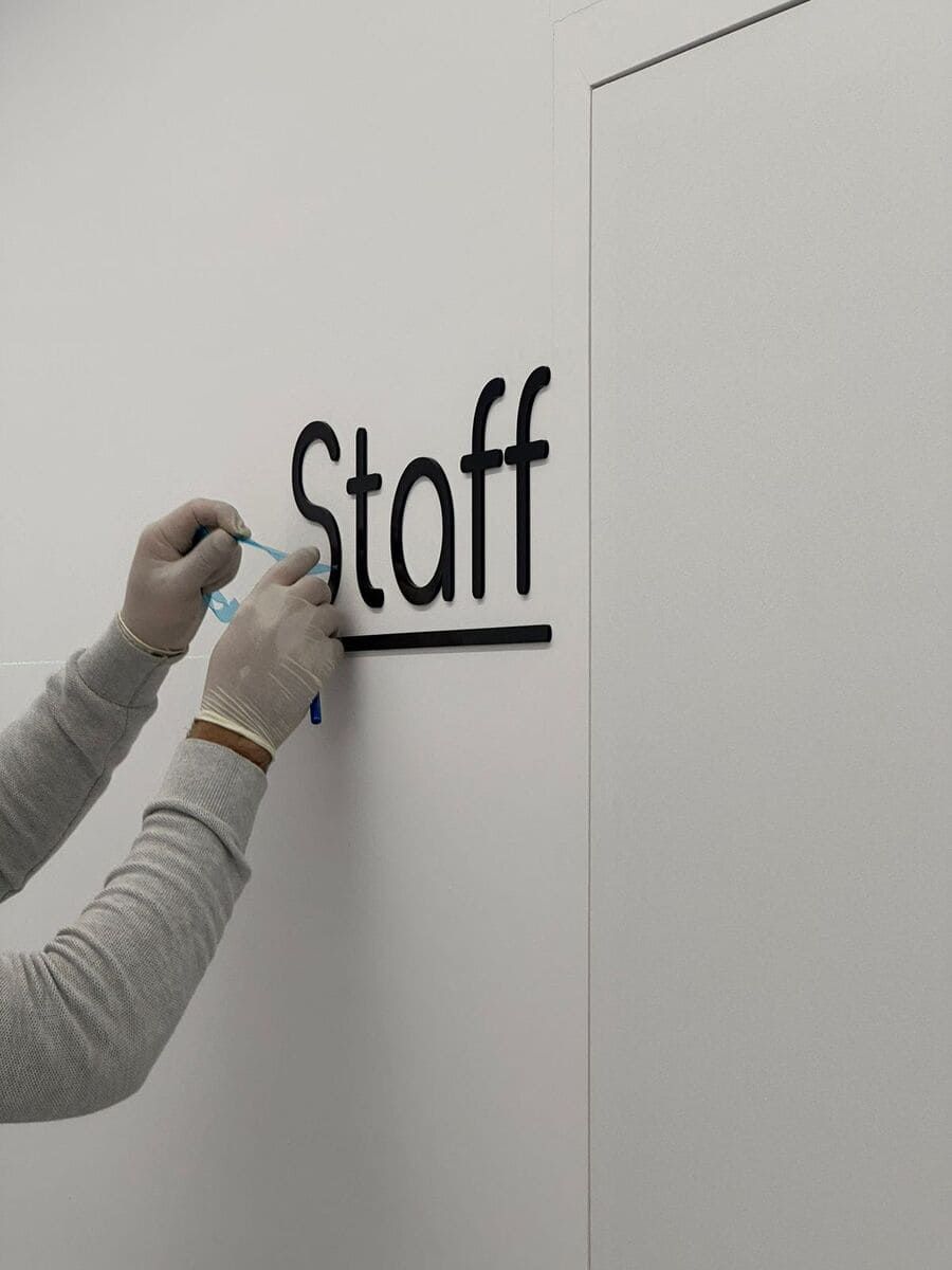 Una persona está escribiendo la palabra personal en una pared blanca.