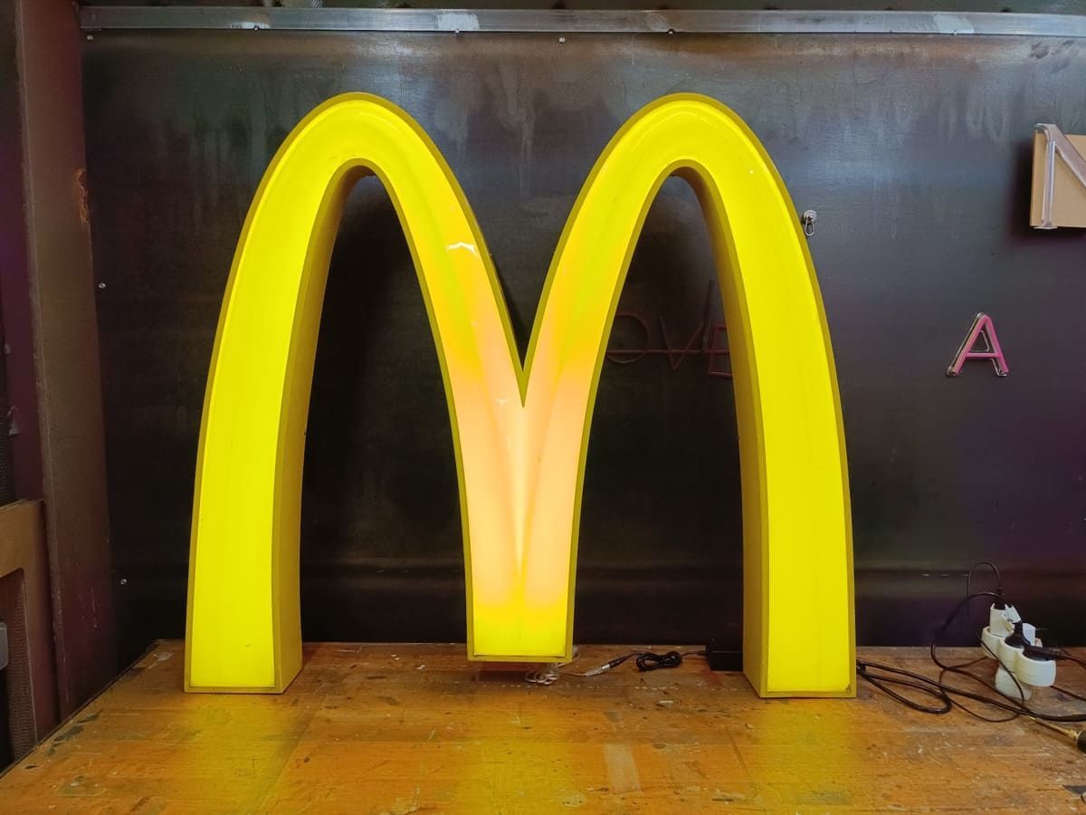 Un gran cartel amarillo de McDonald's está sobre una mesa de madera.