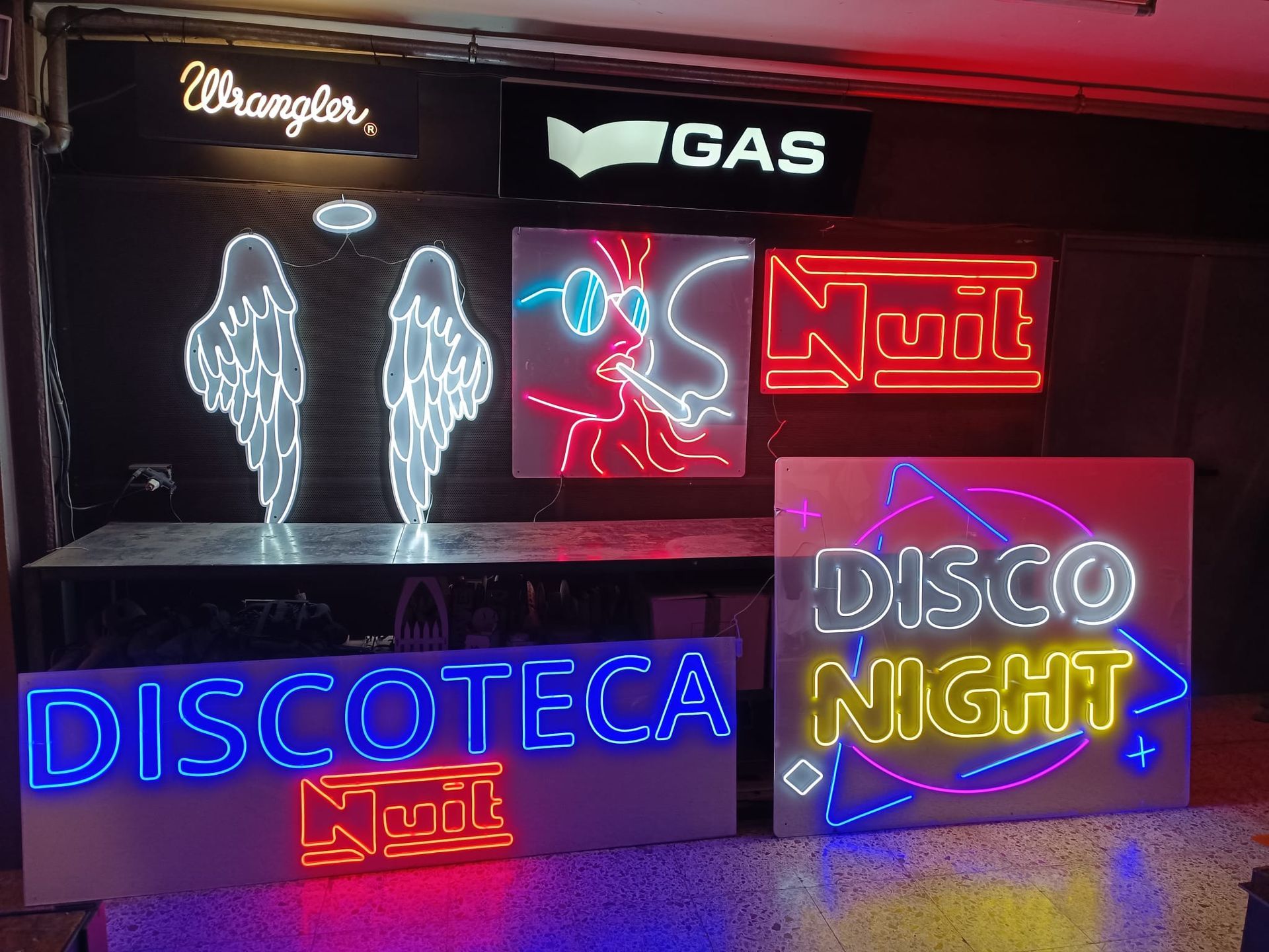 Un letrero de neón está sobre una mesa de madera al lado de una caja de madera.