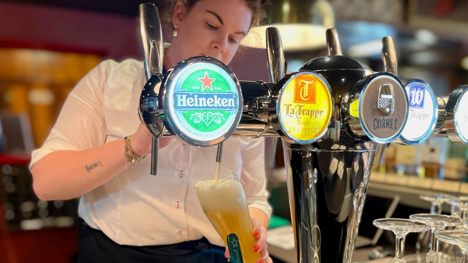 Barkeeper schenkt in einer Bar Bier aus einem Heineken-Zapfhahn ein.