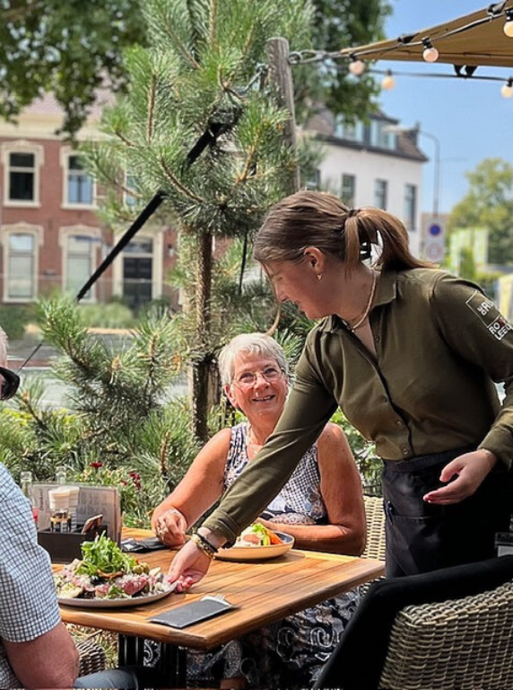 Een serveerster draagt ​​twee borden met eten in een restaurant.