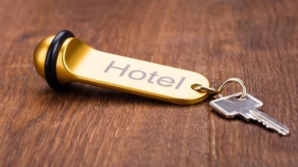 Goldener Hotelschlüssel mit der Aufschrift „Hotel“ und einem Schlüsselring auf einer Holzoberfläche.