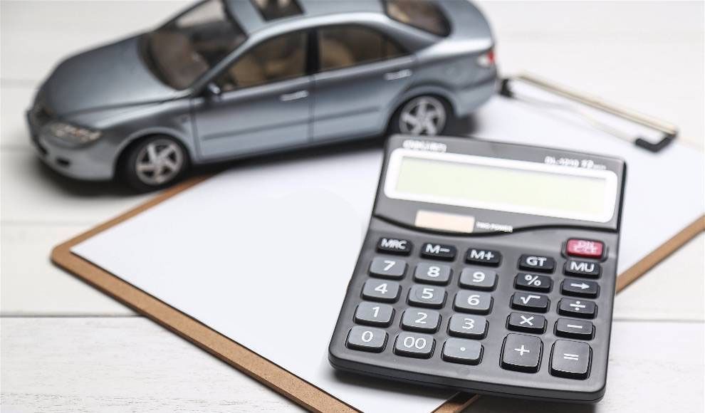 Un coche de juguete está al lado de una calculadora en un portapapeles.