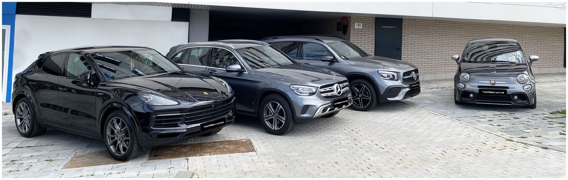 Una fila de coches están aparcados delante de un edificio.