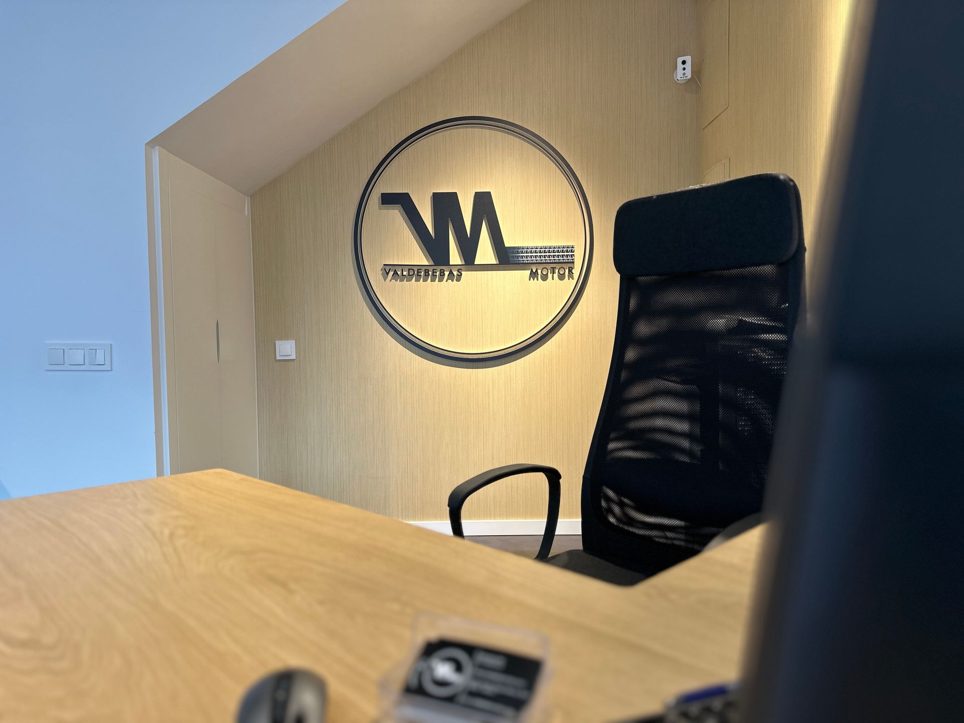 Un escritorio con una silla y un logotipo en la pared.