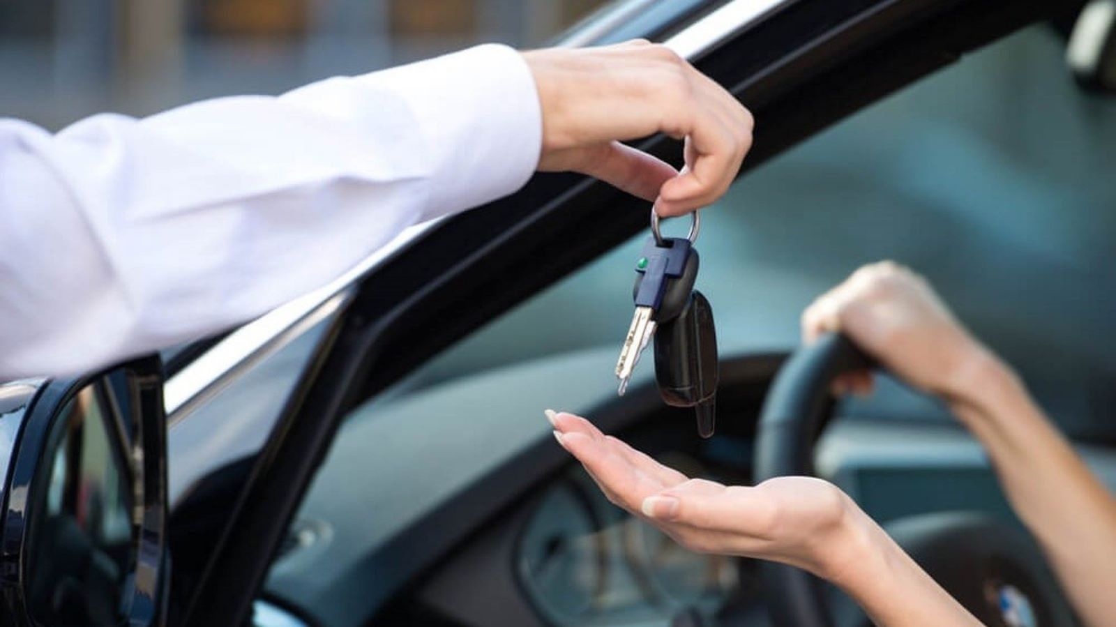 Un hombre le entrega una llave de coche a una mujer en un coche.