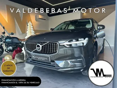 Un automóvil Volvo está en una sala de exposición al lado de una motocicleta.