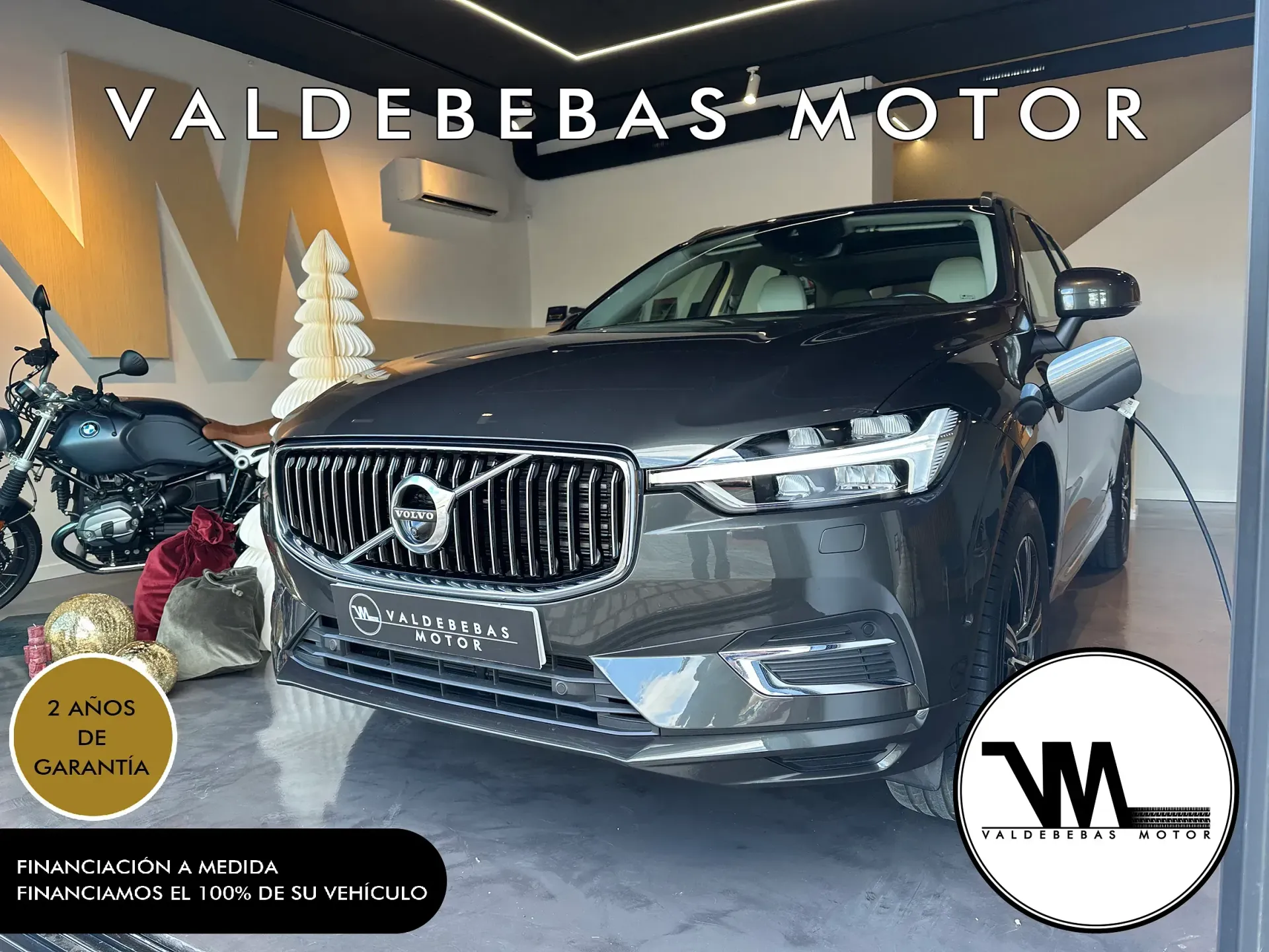 Un automóvil Volvo está en una sala de exposición al lado de una motocicleta.