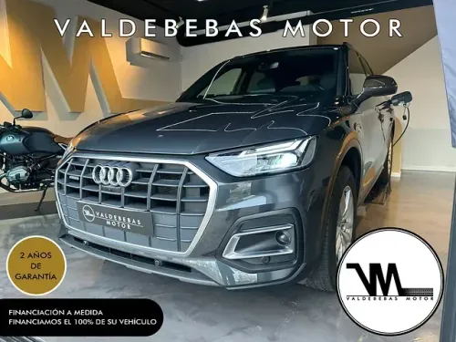 Un Audi Q5 está en una sala de exposición al lado de una motocicleta.