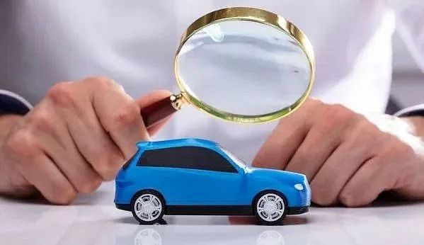 Una persona sostiene una lupa sobre un coche de juguete.