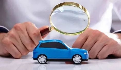 Una persona sostiene una lupa sobre un coche de juguete.