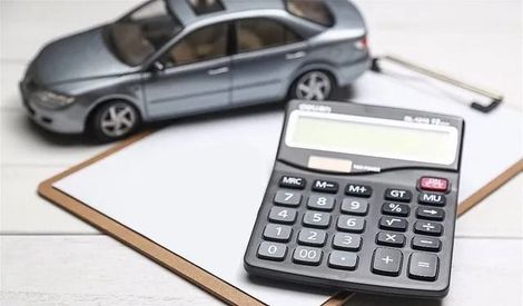 Un coche de juguete está al lado de una calculadora en un portapapeles.