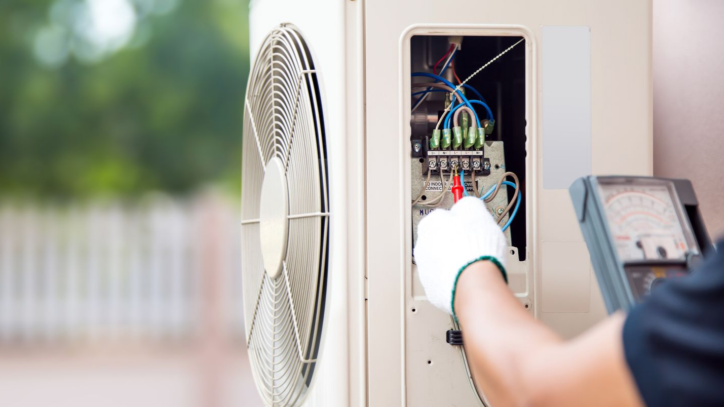 Un technicien prend des mesures au niveau d'une pompe à chaleur.