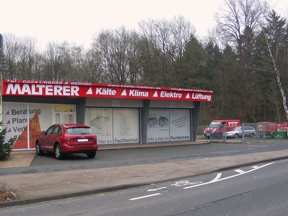 Ein rotes Auto steht vor einem Gebäude mit der Aufschrift Malterer