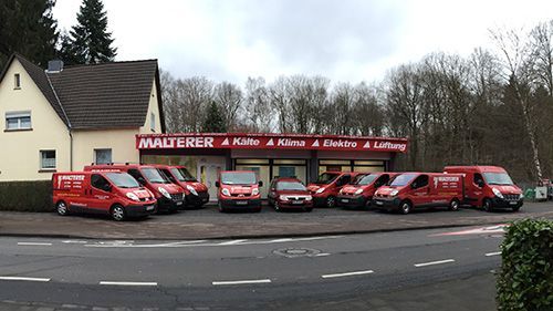 Eine Reihe roter Lieferwagen parkt vor einem Gebäude mit der Aufschrift „Malerer“