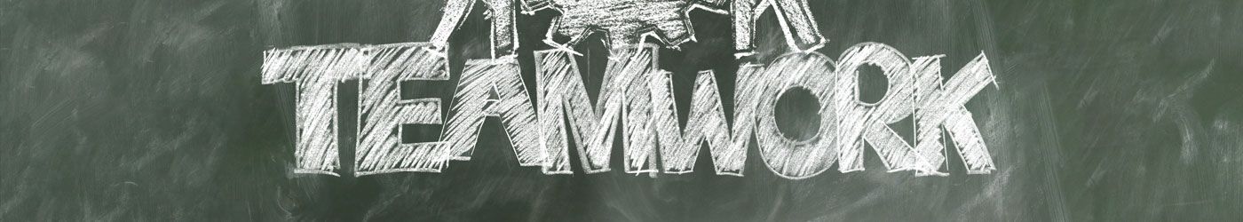 Das Wort Teamwork steht mit weißer Kreide auf einer Tafel
