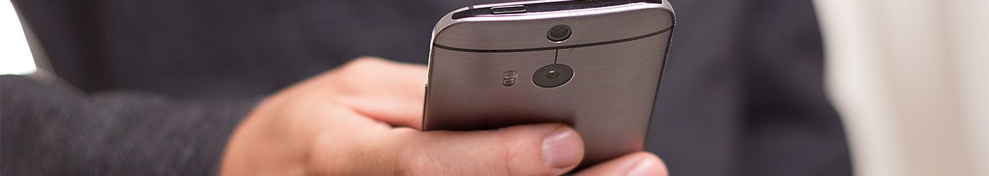 Ein Mann im Anzug hält ein Mobiltelefon in der Hand.