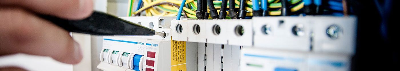 Eine Nahaufnahme der Hand einer Person, die einen Bleistift vor einem Schaltkasten hält.