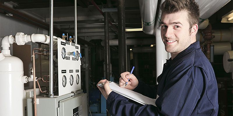 Ein Mann schreibt in einer Fabrik auf einem Klemmbrett
