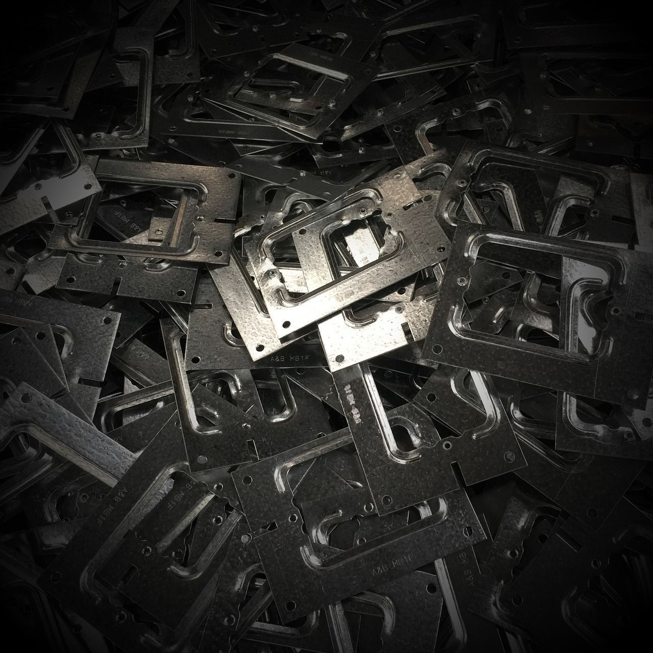 Pila de soportes metálicos estampados con diversos recortes y agujeros, probablemente para construcción o montaje.